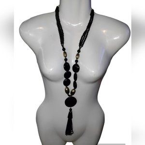 black gold beaded necklace with hanging tassle off of disc pendant